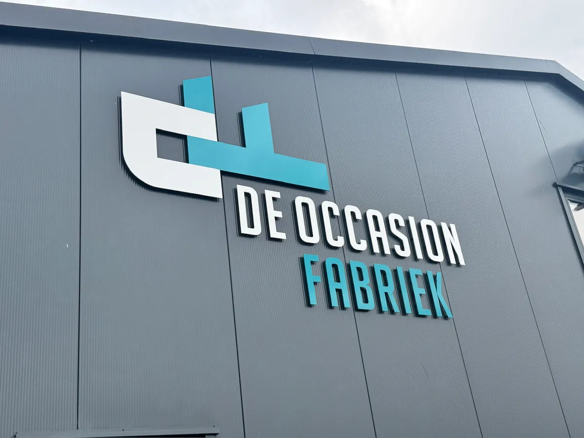 Logo en letters DE OCCASION FABRIEK in wit en turquoise op de donkergrijze gevel