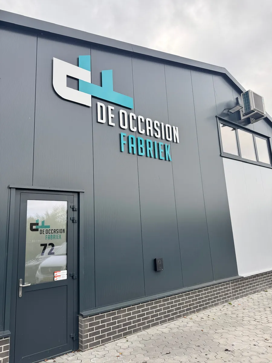 Gevel met het logo De Occasion Fabriek en belettering op de deur