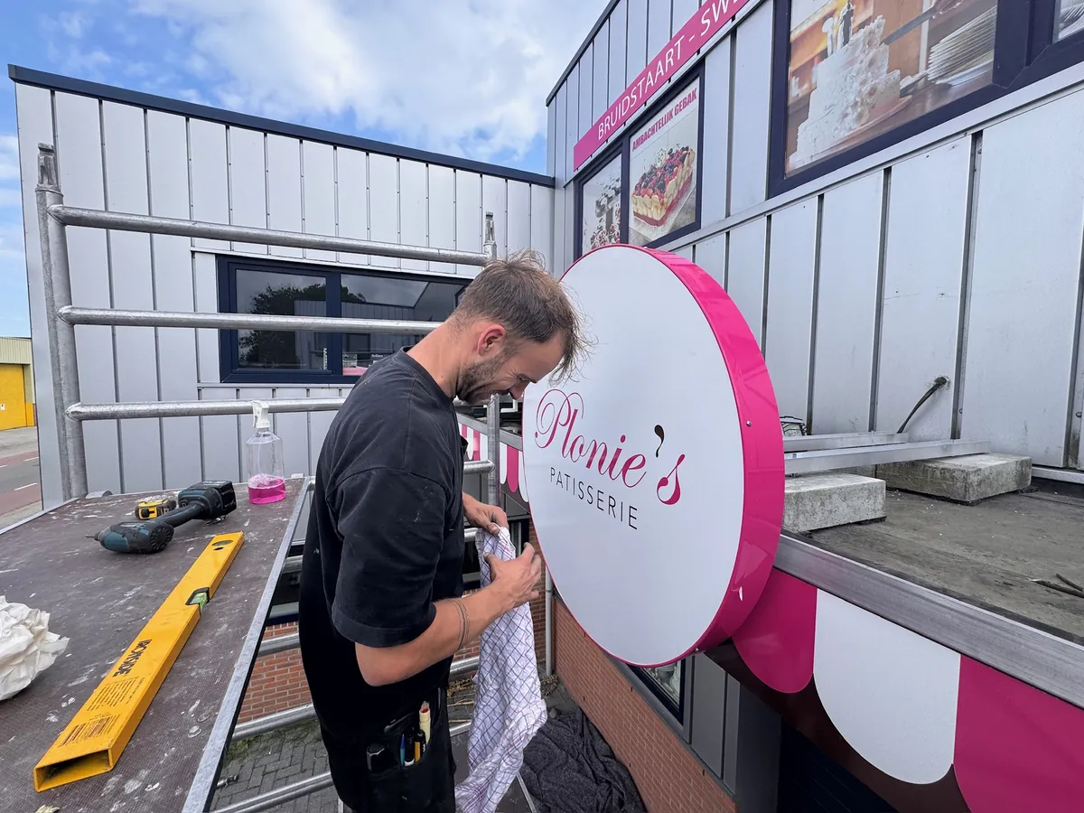 Monteur werkt het ronde roze bord af op het dak