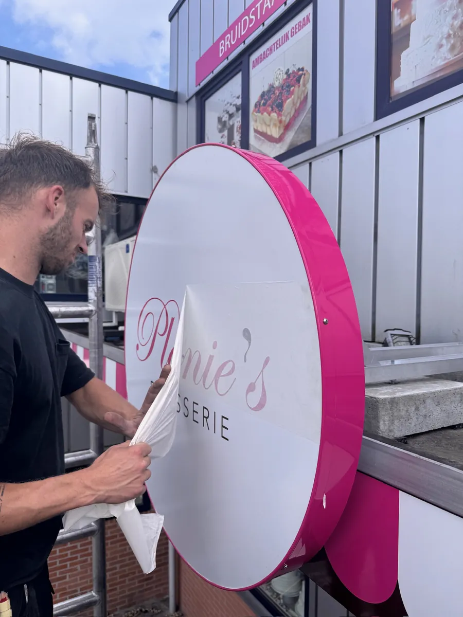Monteur trekt de folie van het ronde bord van Plonie's Patisserie