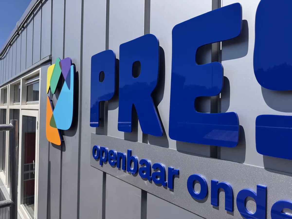 Blauwe letters PRESENT en openbaar onderwijs op de grijze gevel, van dichtbij