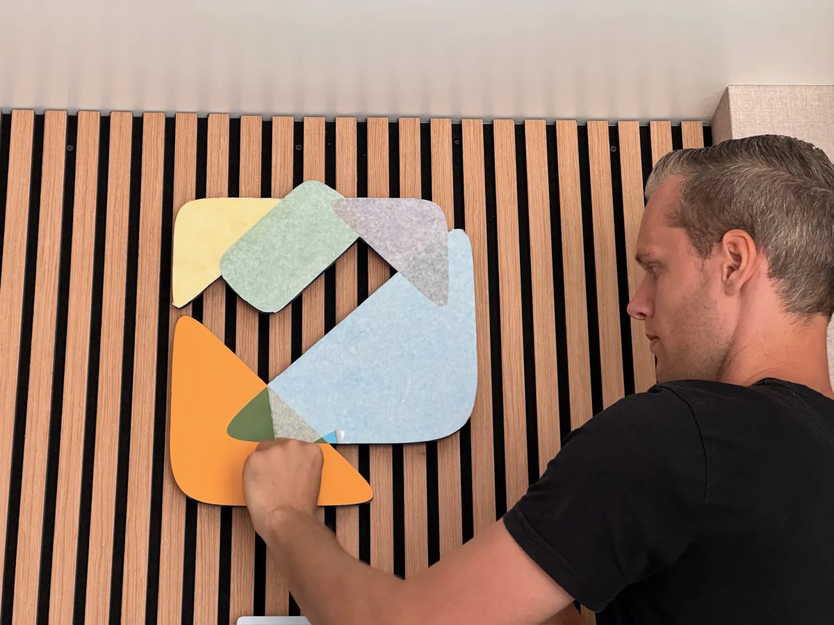 Monteur zet het kleurige logo vast op de houten lamellenwand