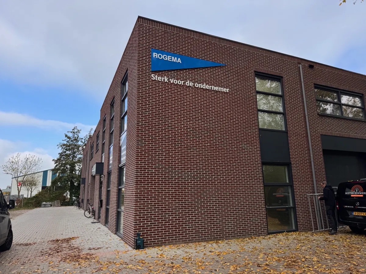 Bakstenen pand met het Rogema-vaantje en de slogan op de hoek