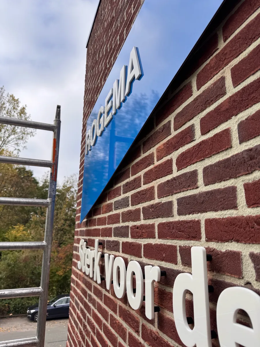 Blauw Rogema-vaantje en witte letters Sterk voor de op baksteen, van dichtbij