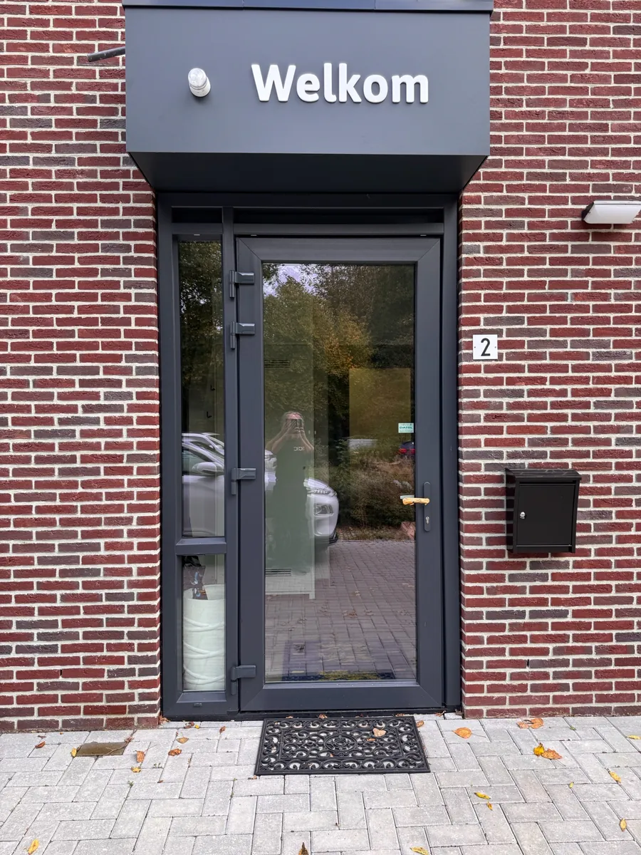Luifel met het woord Welkom boven de glazen entreedeur