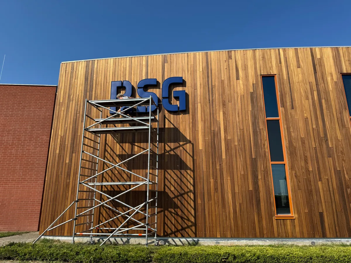 Blauwe letters RSG op de gebogen houten gevel met de steiger ervoor