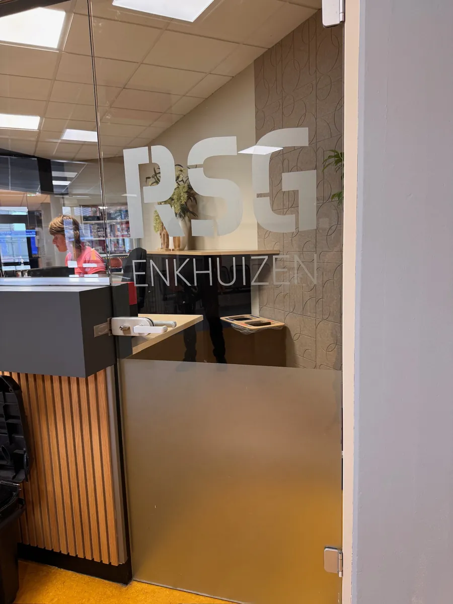 Zandstraalfolie met RSG Enkhuizen op de glazen wand naast de balie