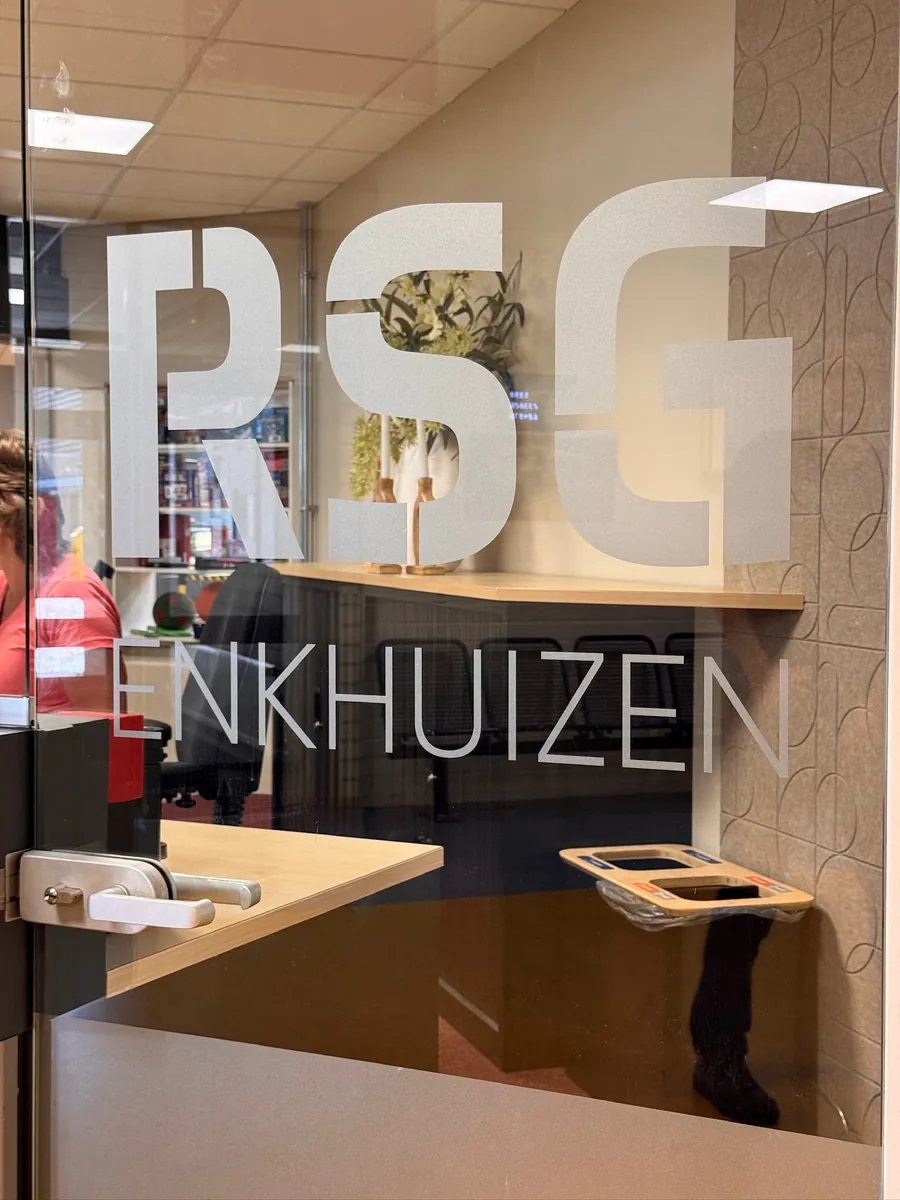 Grote letters RSG en Enkhuizen in zandstraalfolie op glas, van dichtbij