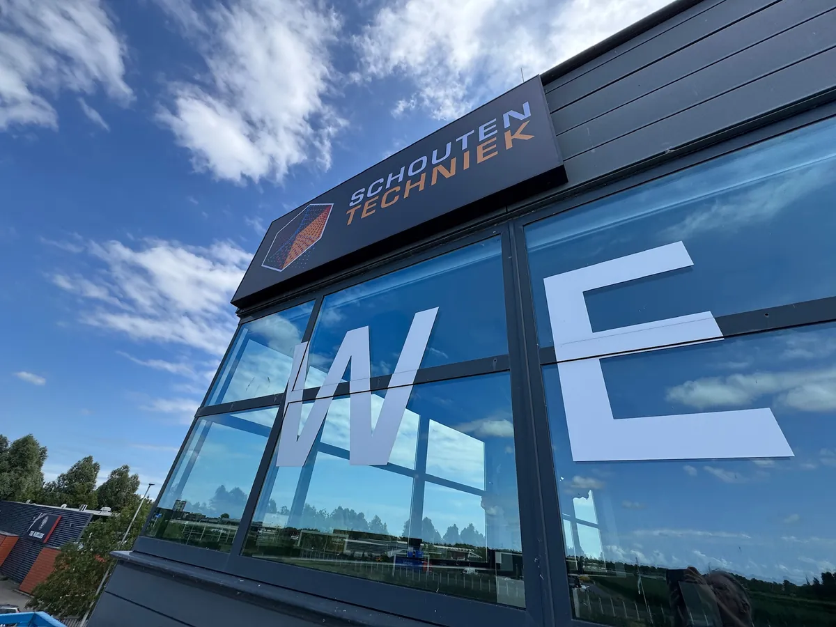 Bord met Schouten Techniek boven grote witte letters op de glazen gevel