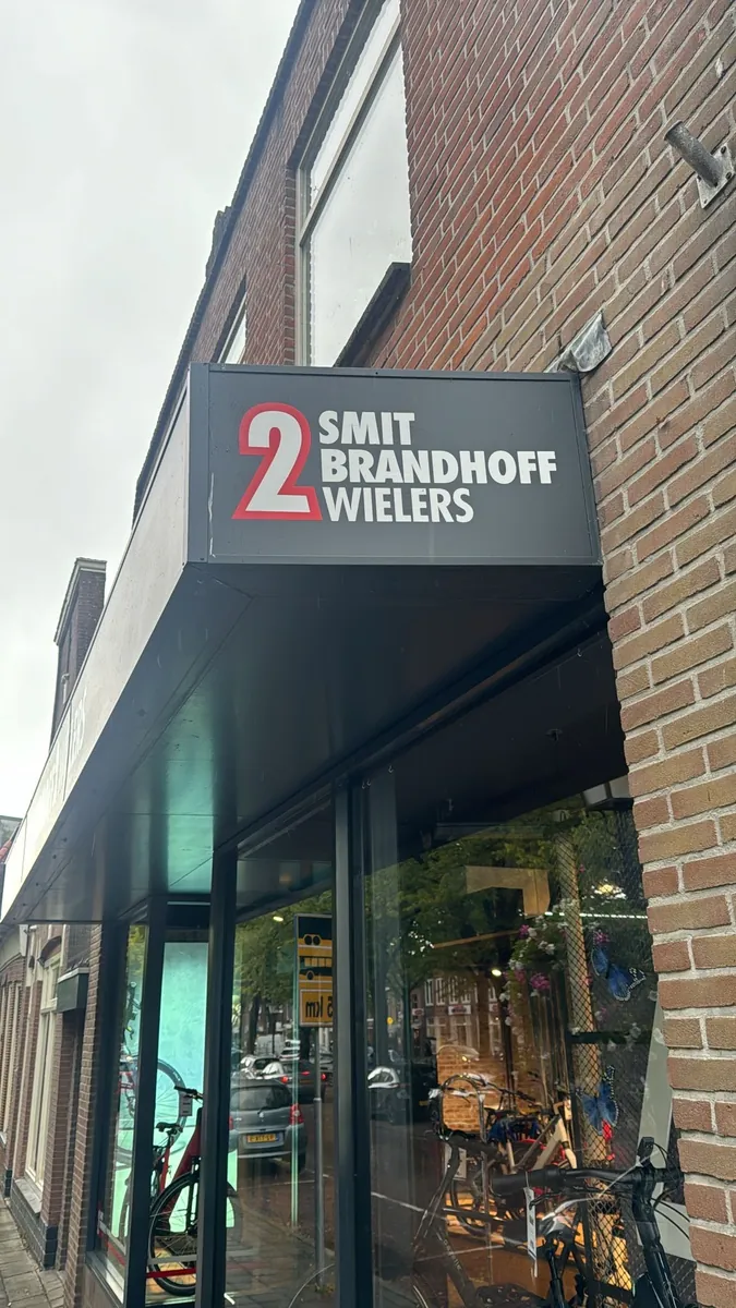 Donker gevelbord van Smit Brandhoff Wielers op de luifel boven de winkelpui