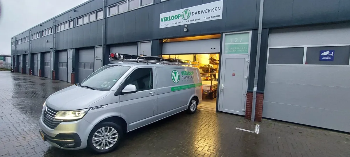 Zilveren bus met belettering van Verloop Dakwerken voor het bedrijfspand