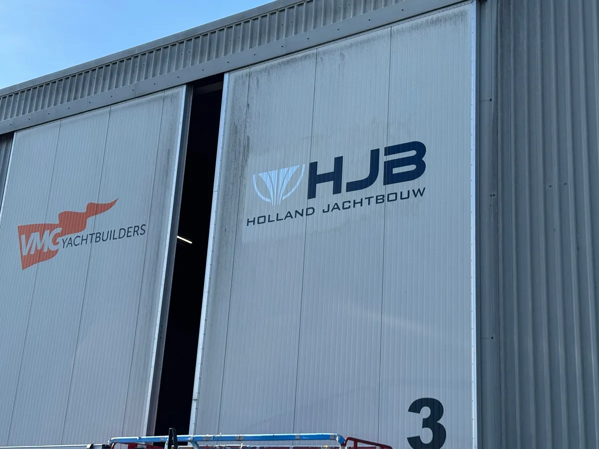 Grijze schuifdeuren met de logo's van VMG Yachtbuilders en HJB