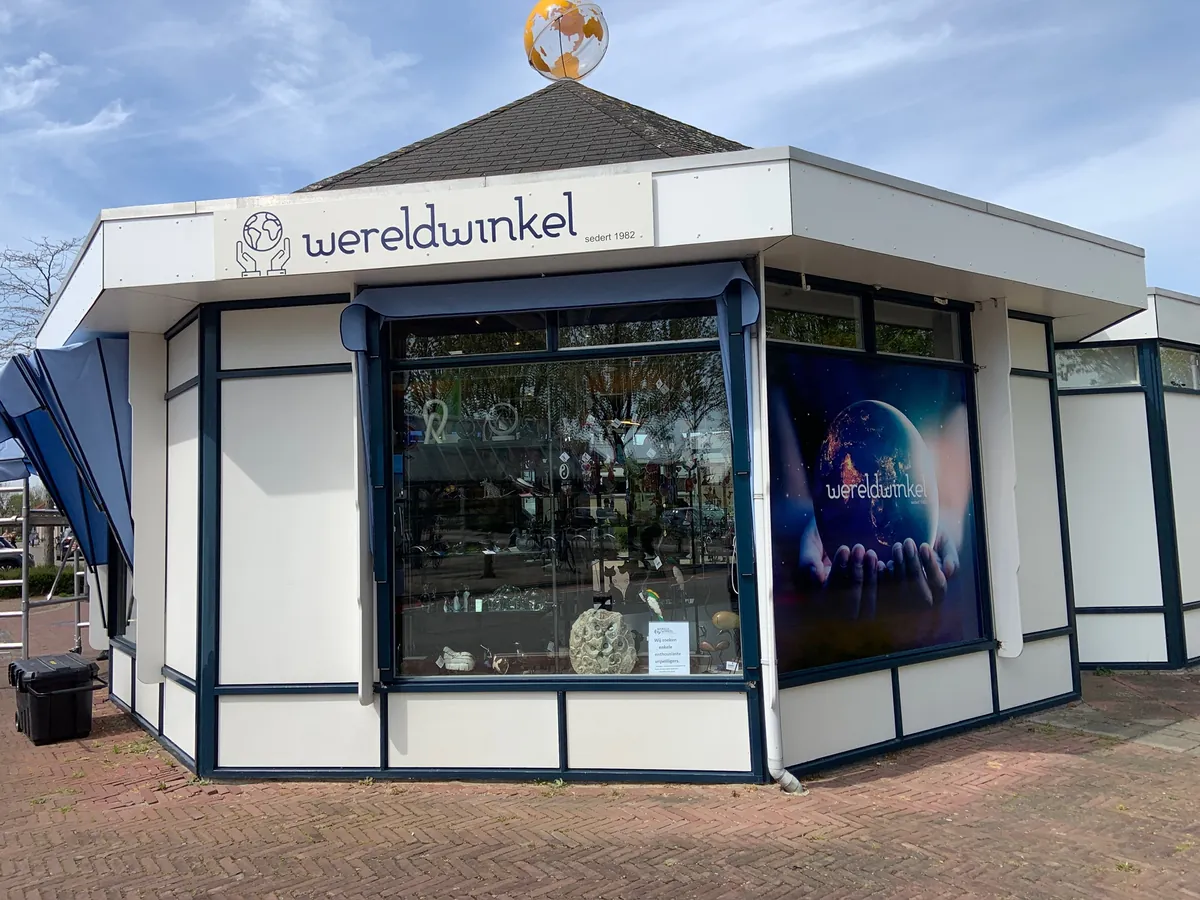 Achthoekig winkelpaviljoen met de naam wereldwinkel en een wereldbol op het dak