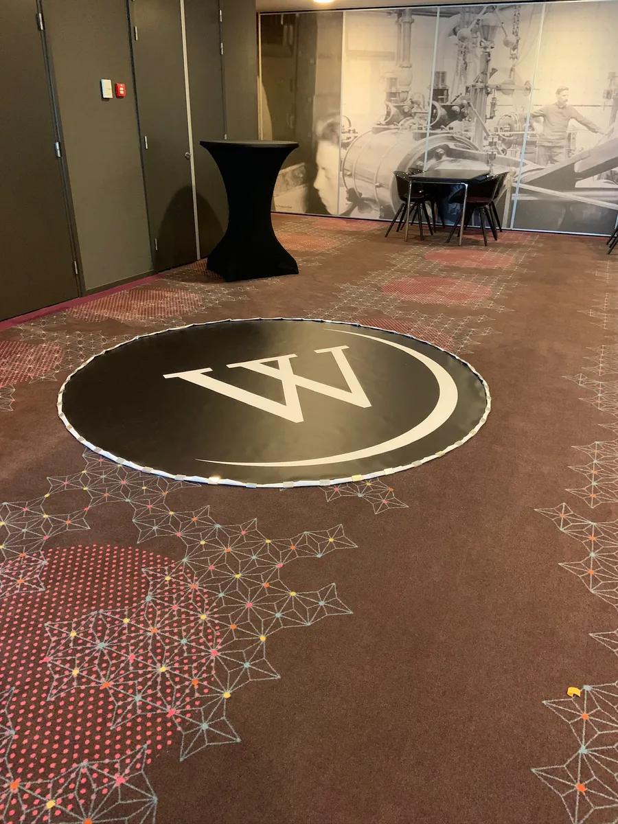 Rond W-logo verwerkt in de vloer van een zaal
