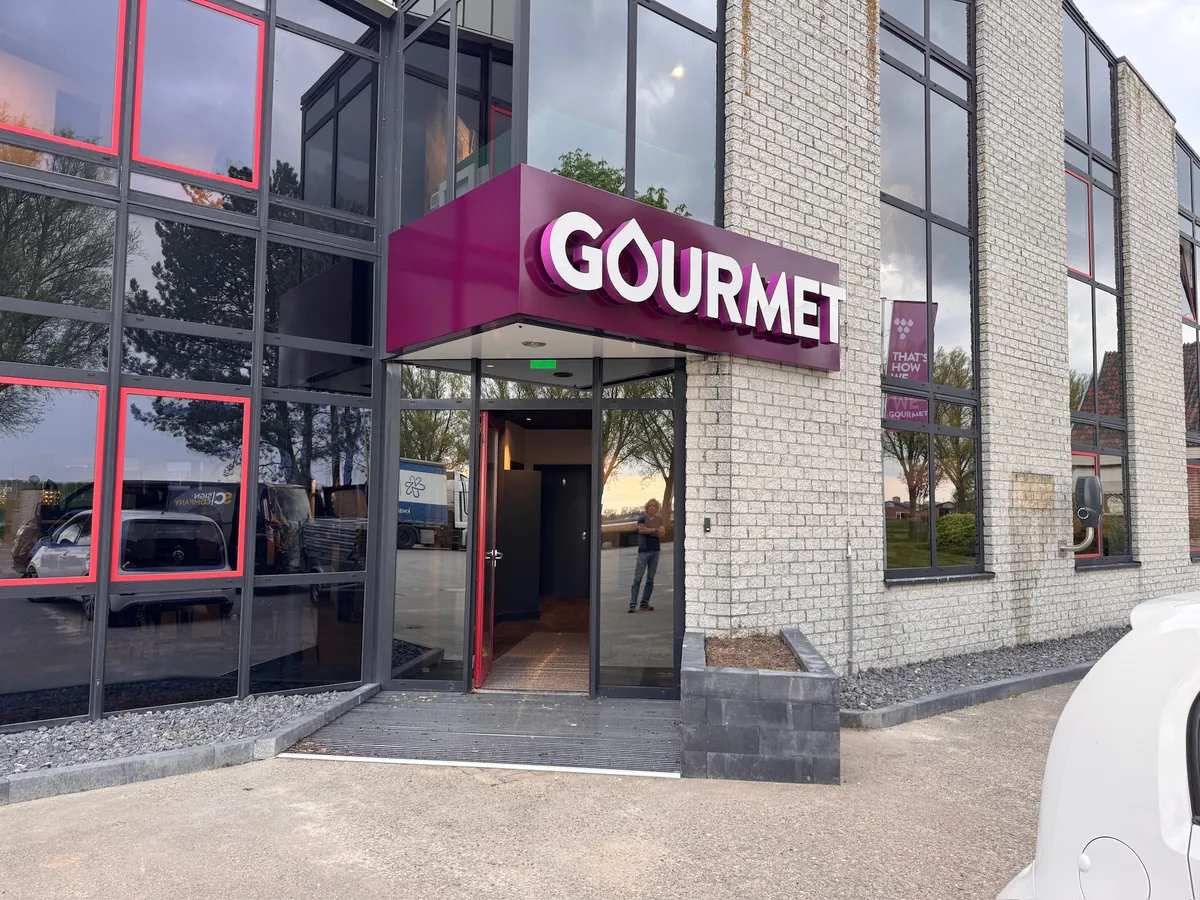 Paarse luifel GOURMET boven de glazen entree, schuin gezien