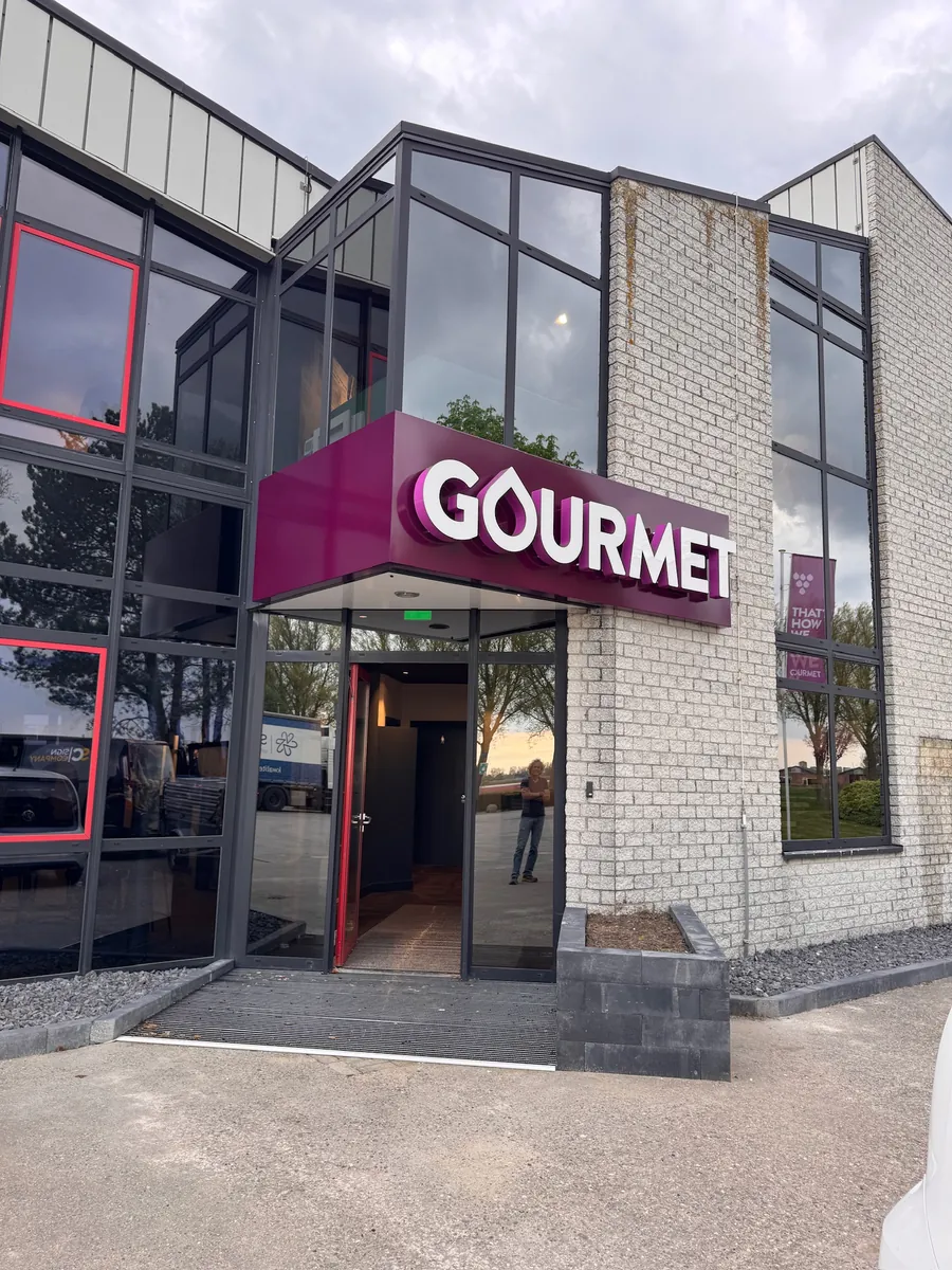 Paarse luifel met de letters GOURMET boven de glazen entree
