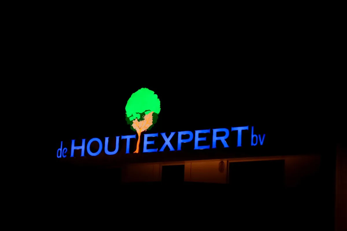 Verlichte doosletters de Hout Expert met groen boomlogo in het donker