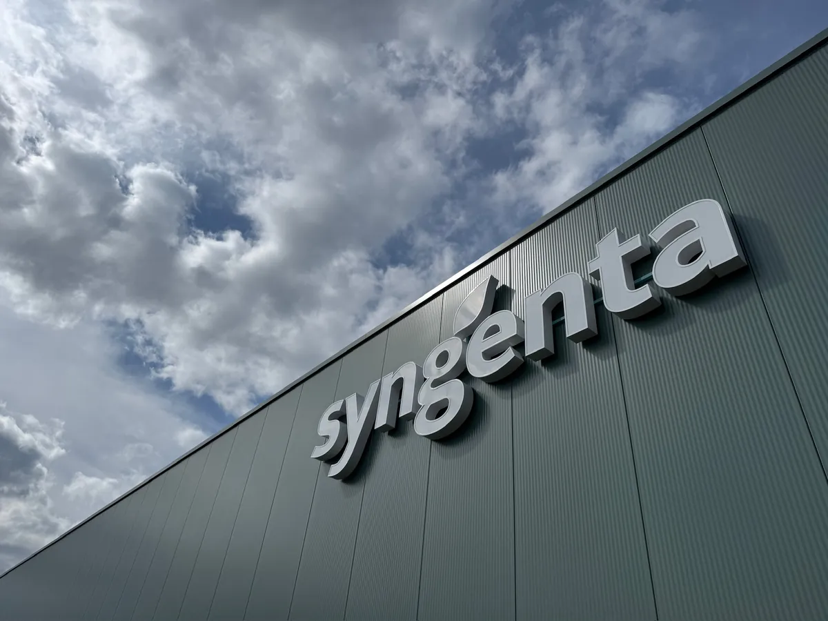 Letters syngenta op de groene gevel tegen een wolkenlucht, van onderaf