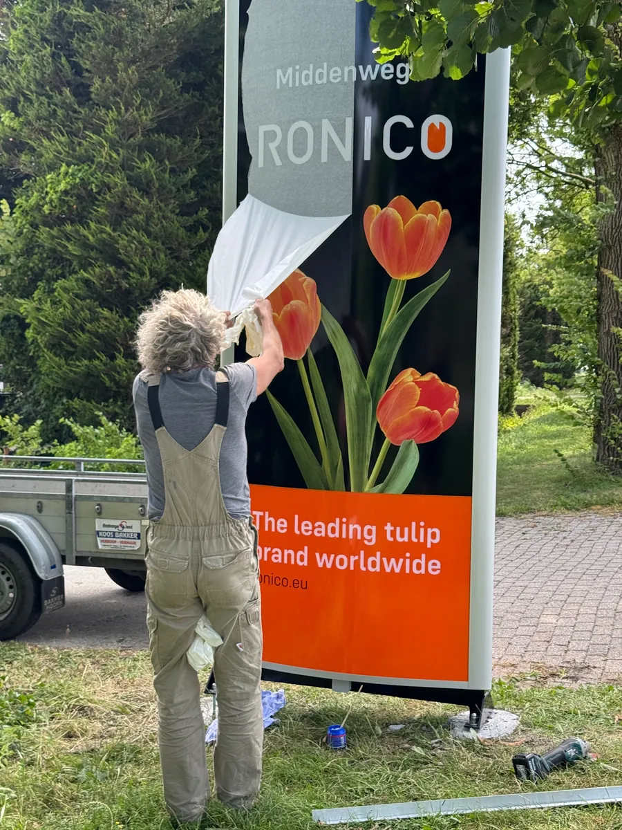 Monteur trekt de folie van de reclamezuil van Ronico