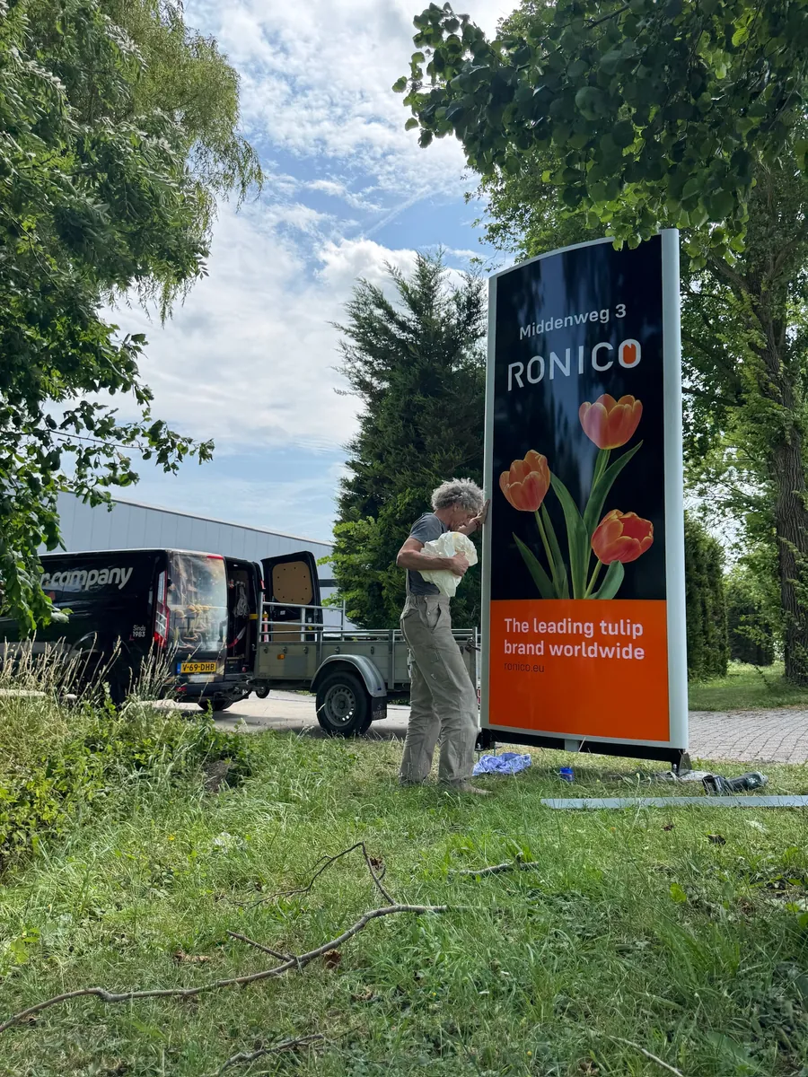 Monteur bij de reclamezuil van Ronico met tulpen