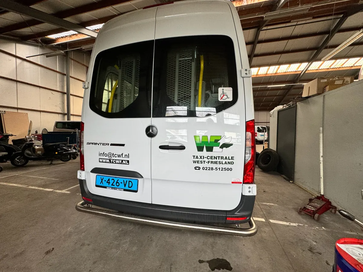 Achterkant van een witte bus met het logo en de gegevens van Taxi-Centrale West-Friesland