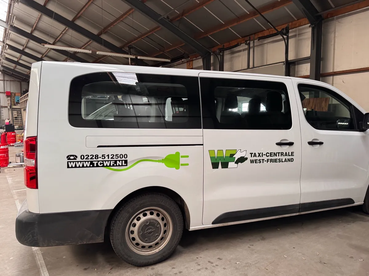 Witte bus met telefoonnummer, website en groene stekker-lijn